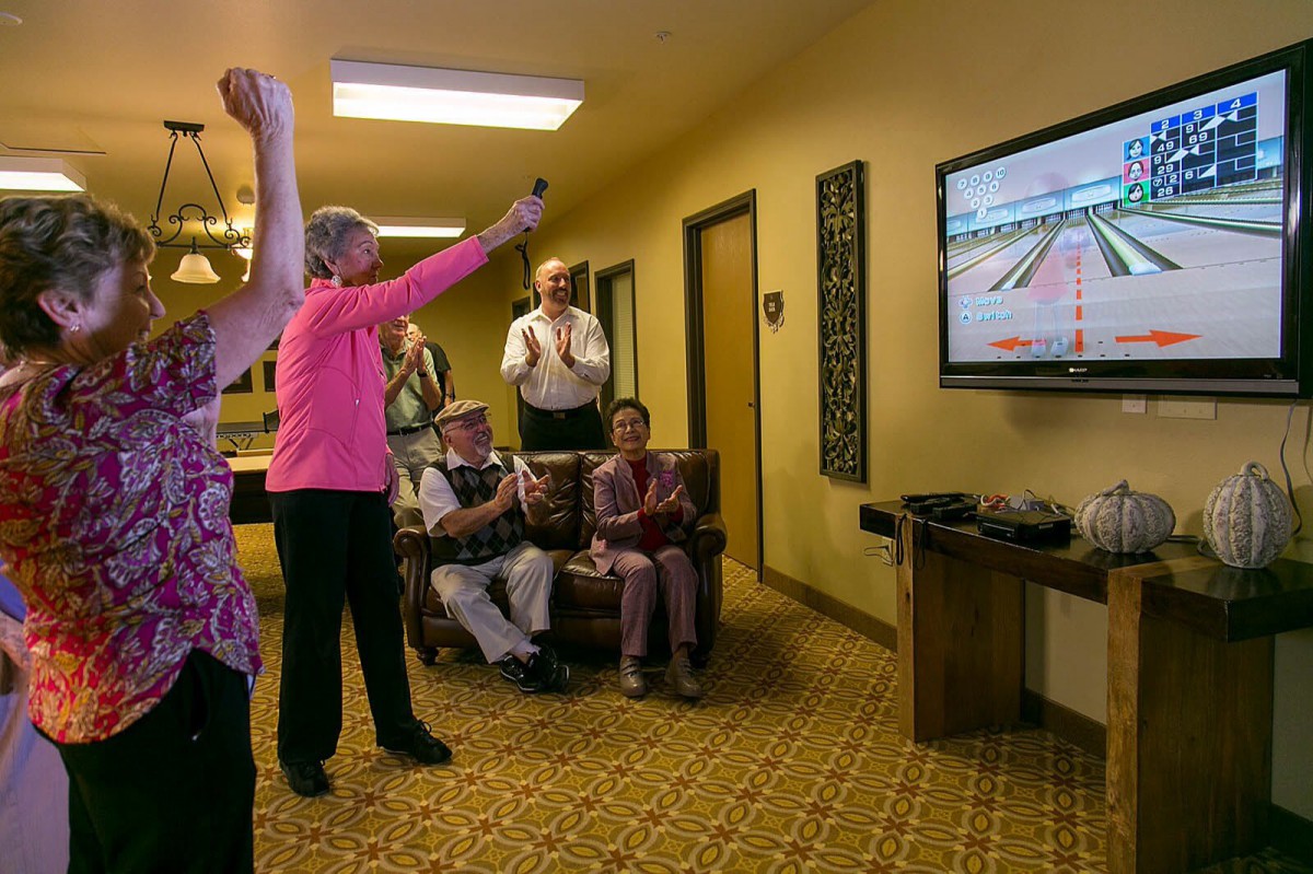 A group of seniors enjoying a bowling video game together indoors.