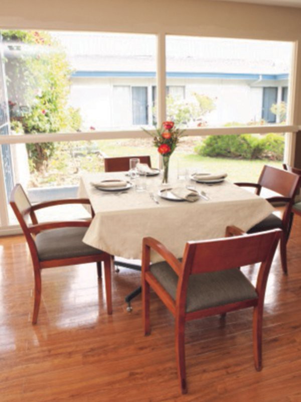 A dining table set for four, with natural light streaming through large windows.