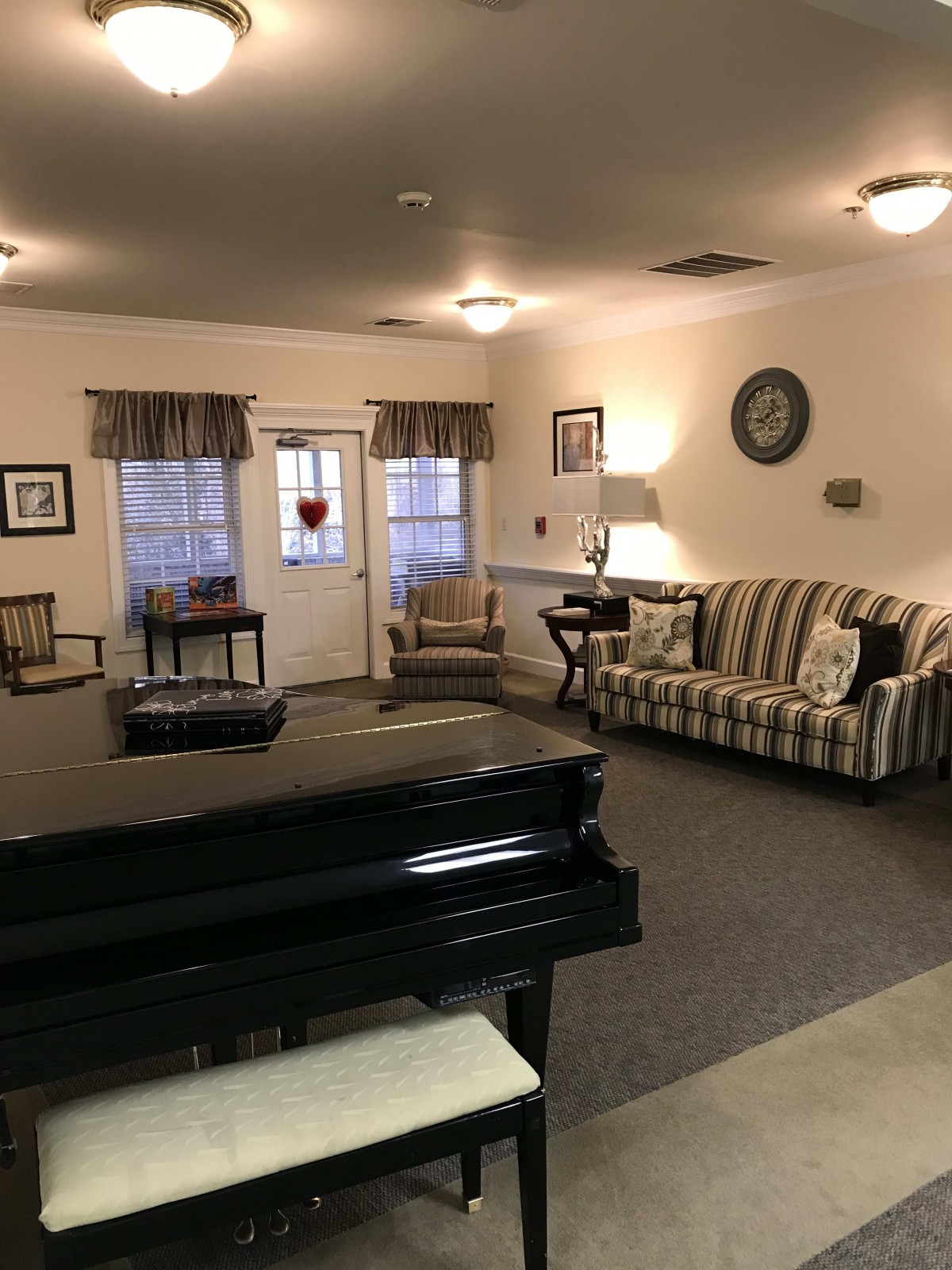 A cozy living room with a piano, sofa, chairs, and decor.