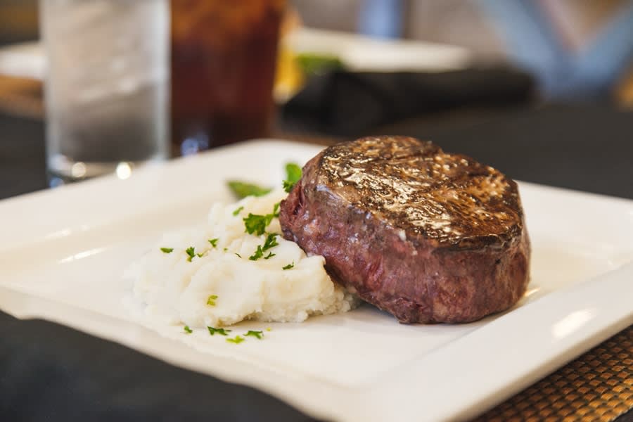 A deliciously cooked steak served with a side of mashed potatoes.