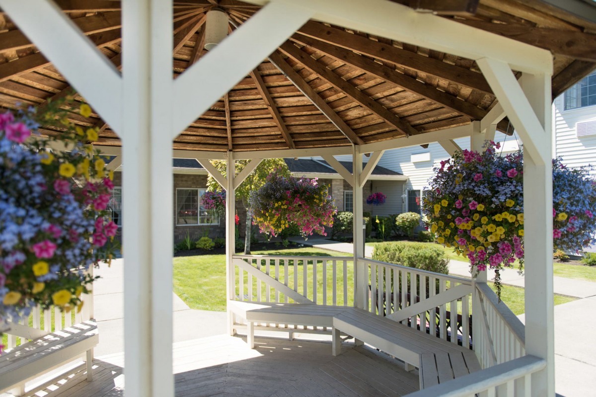 A peaceful gazebo surrounded by a well-kept garden with hanging flower baskets.