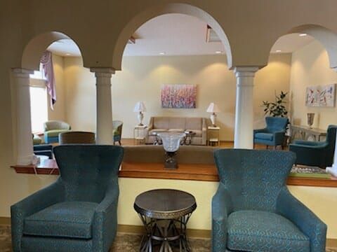 A cozy lounge area featuring armchairs and a sofa, separated by elegant archways.