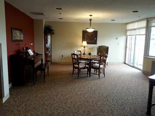 A spacious dining area featuring a table and chairs, complemented by warm lighting and soft carpeting.