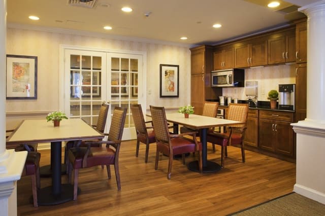 A modern dining and kitchen area featuring wooden floors, tables, chairs, and well-lit interior.