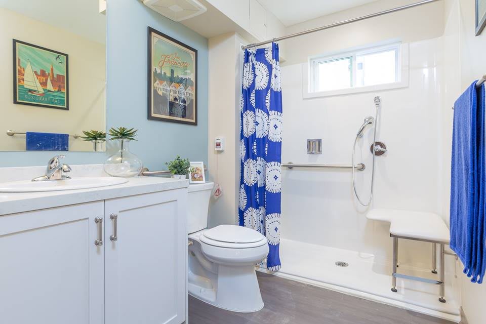 A modern bathroom with a blue shower curtain, white vanity, and sleek fixtures.