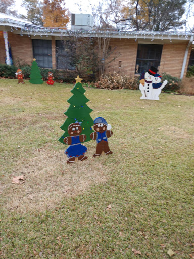 A cheerful Christmas scene featuring a decorated tree and festive figures in a front yard.