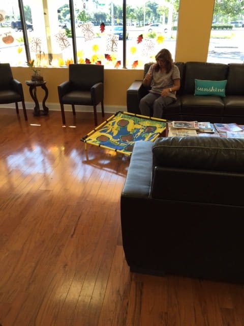 A waiting room with seating and a woman sitting on a couch.