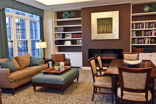 A cozy living room featuring modern furniture, a wooden dining table, and decorative shelves.
