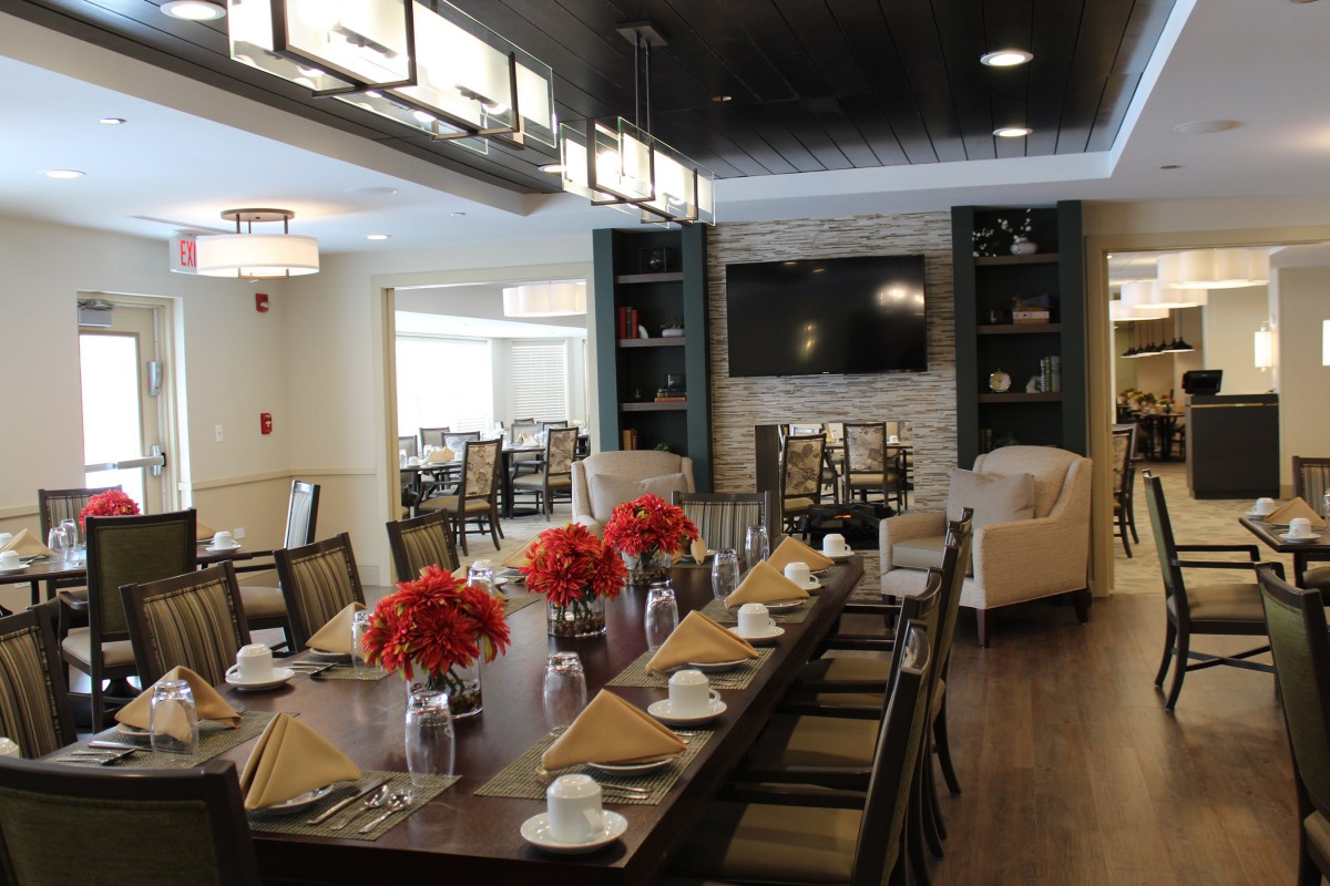 A well-decorated dining room with a large table, elegant lighting, and floral centerpieces.