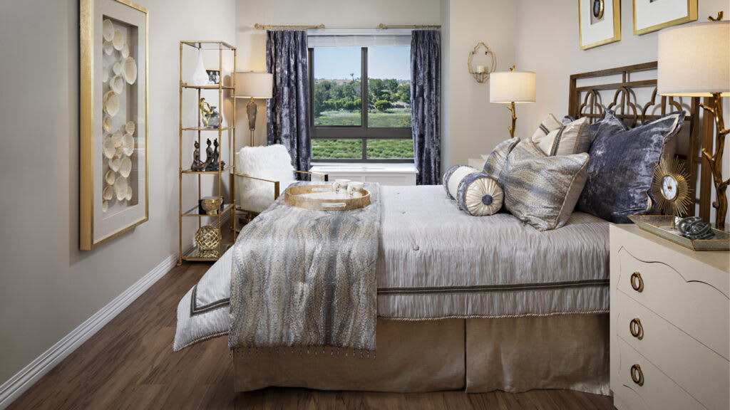 A modern and cozy bedroom with neutral colors, featuring a neatly made bed, stylish decor, and a scenic window view.