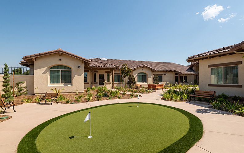 A sunny view of a building with a small putting green in the foreground.