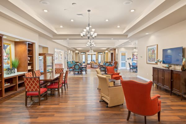 A spacious and elegantly designed lounge area featuring comfortable seating, modern chandeliers, and wooden flooring.