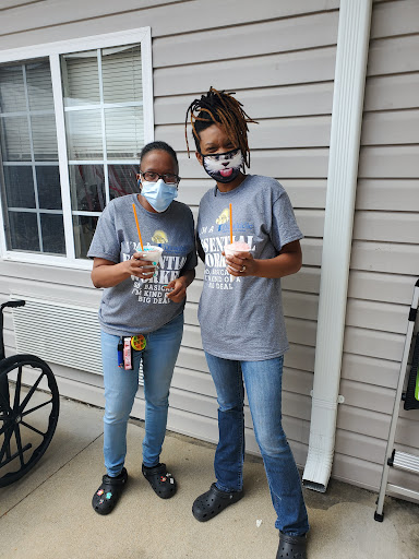 Two individuals enjoying a moment outdoors while wearing masks and casual attire.