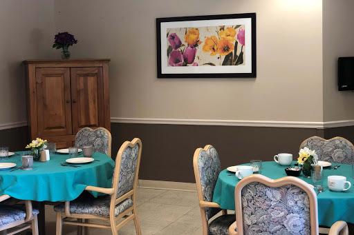 A cozy dining area featuring teal tables and floral artwork on the wall.