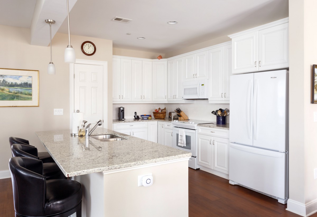 A modern kitchen with white cabinets and a granite countertop island.