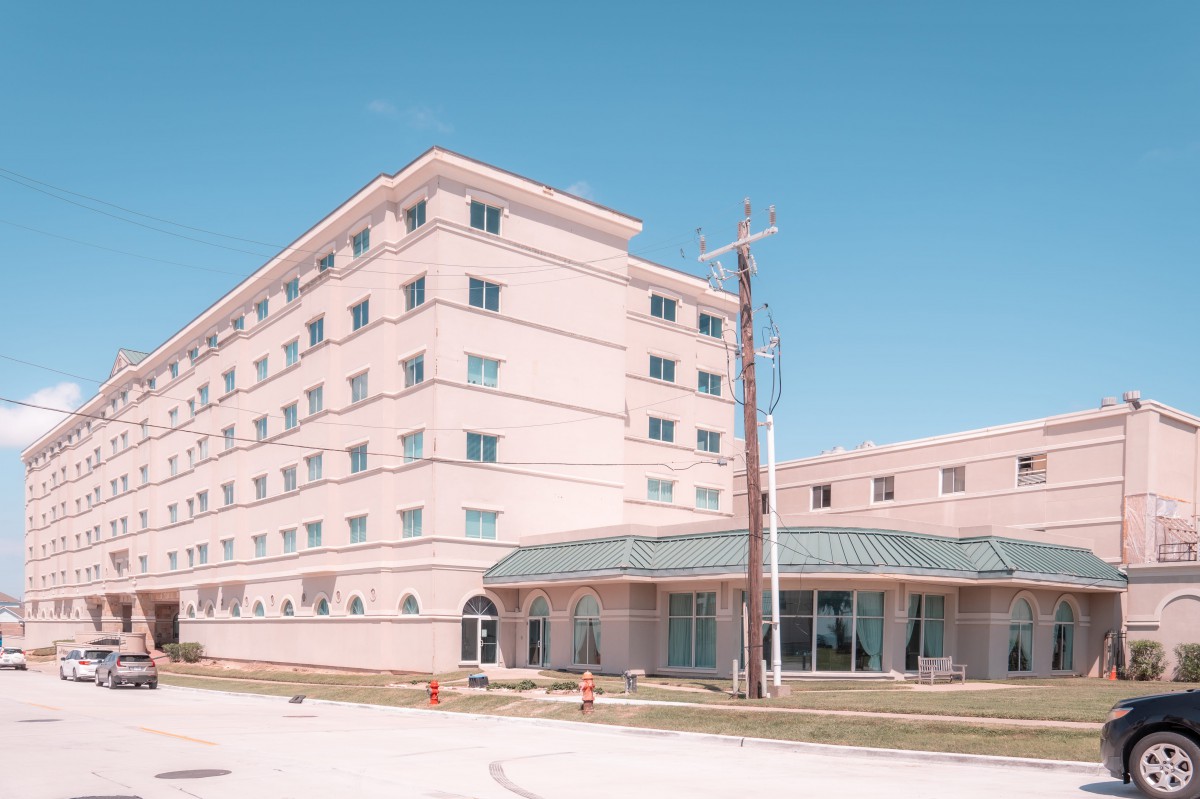 A pink multi-story building with a clear blue sky in the background.