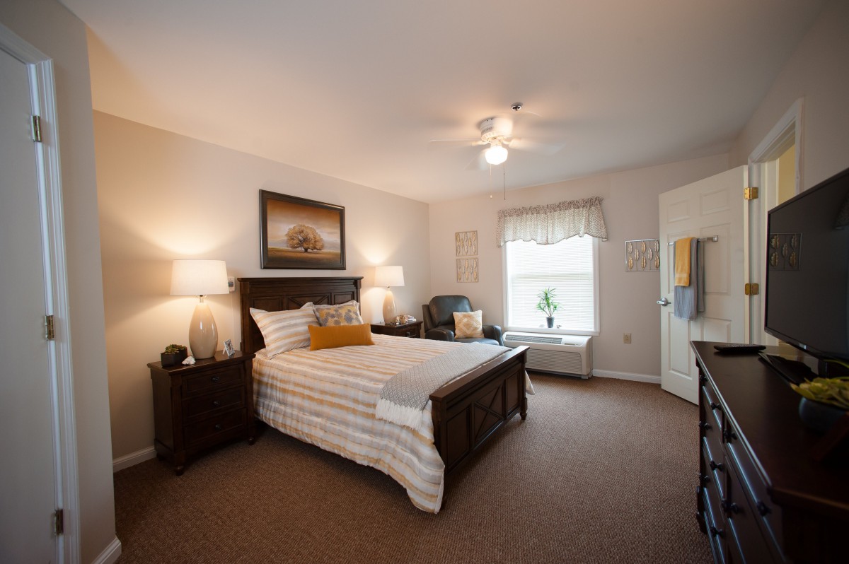 A well-decorated bedroom featuring a bed with striped bedding, two bedside tables with lamps, and a window providing natural light.