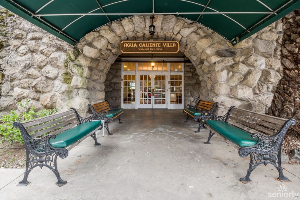 A stone archway entrance with benches and a green awning.