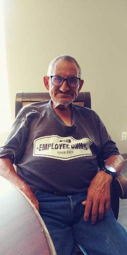 A smiling older man wearing a t-shirt that promotes employee ownership.