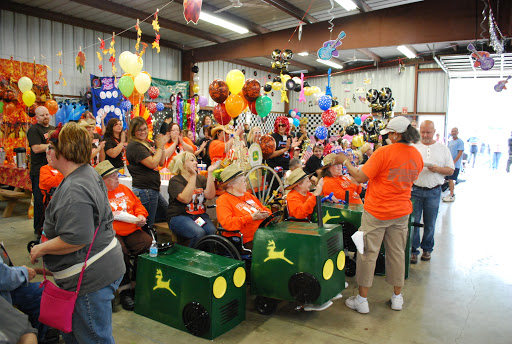 A lively gathering filled with excitement, featuring participants in bright orange shirts and colorful decorations.