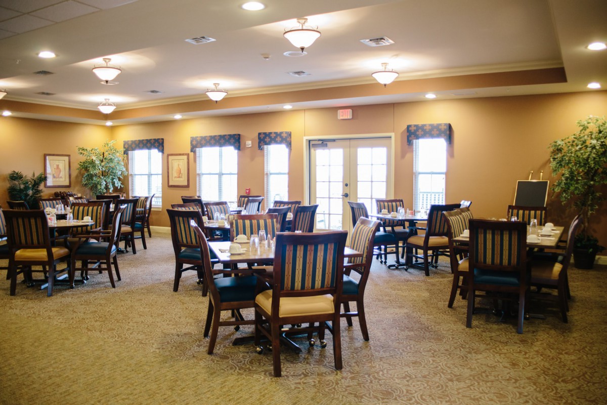 A cozy dining room setup with multiple tables and chairs, featuring warm lighting.