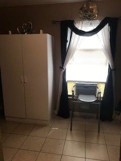 A simple room interior with a wardrobe, chair, and window adorned with curtains.