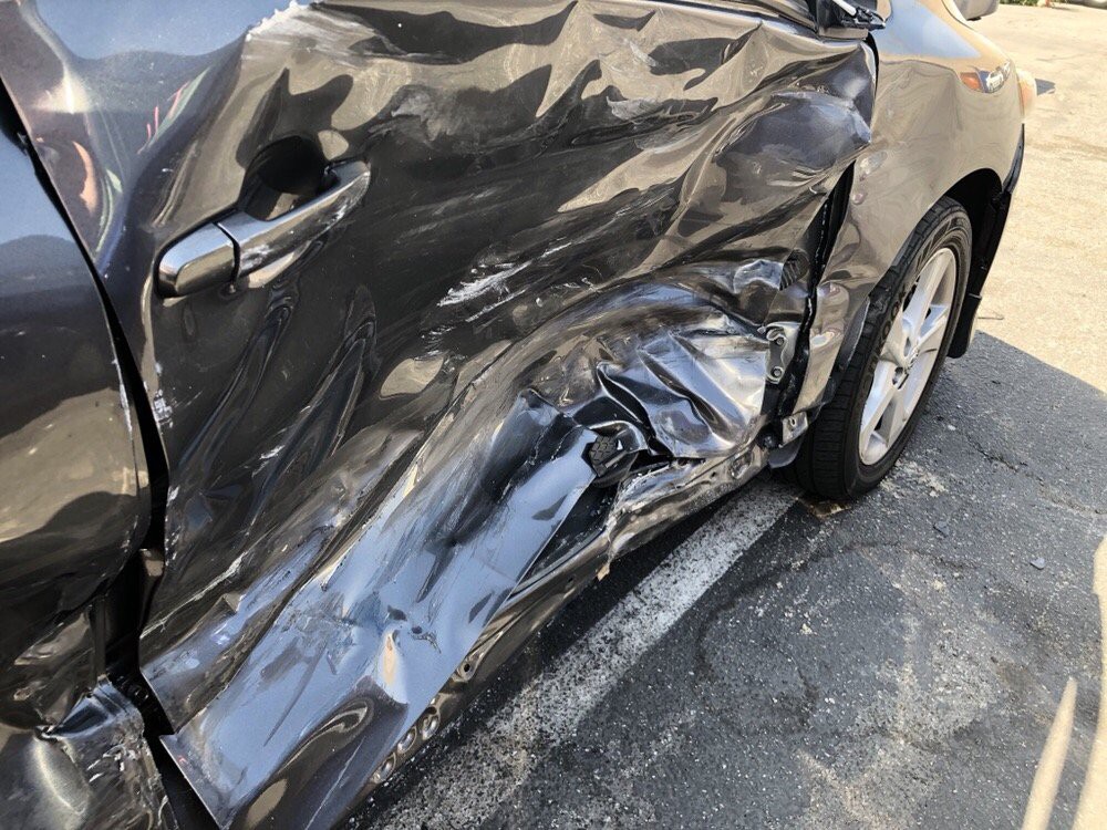 A car with significant side damage, showing dents and scrapes.