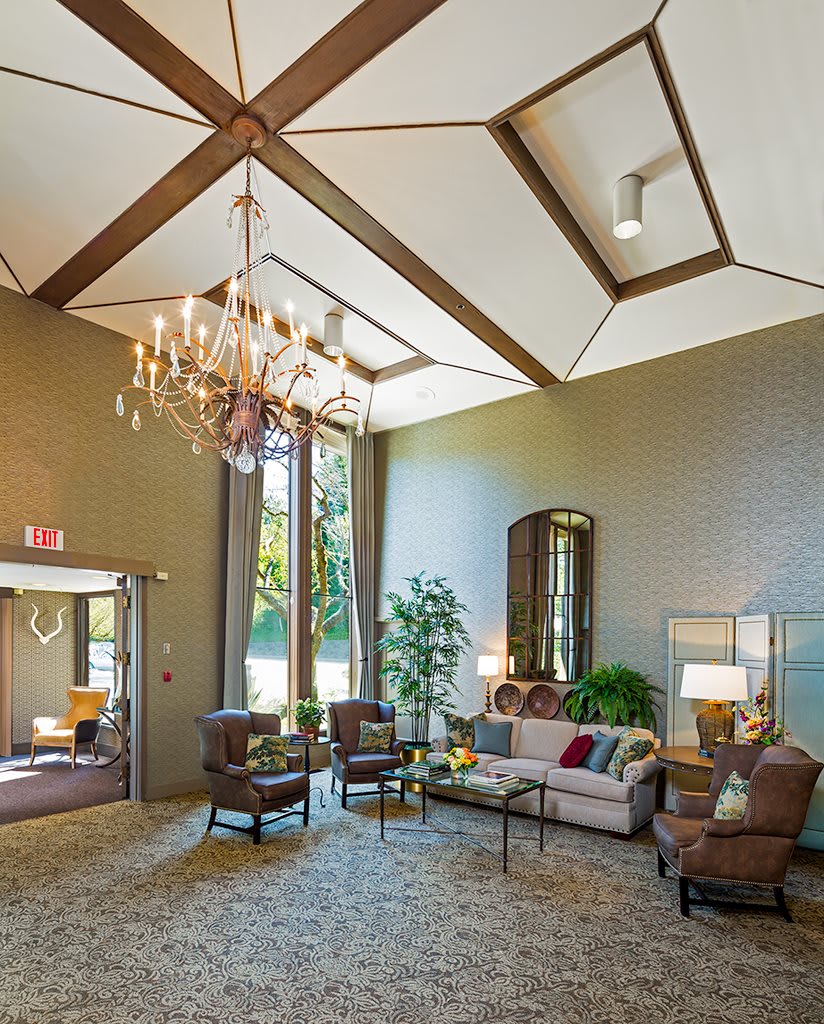 A well-lit lobby with a chandelier, comfortable seating, and high ceilings.