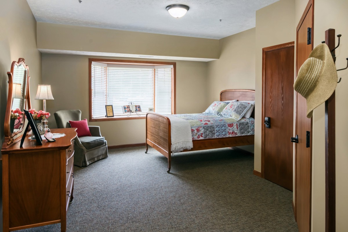 A cozy bedroom with a bed, armchair, and large window.