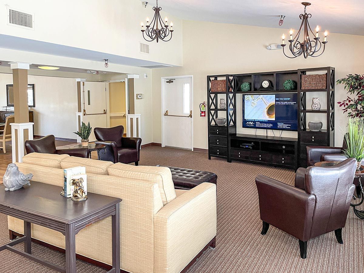 A spacious and elegantly decorated living room featuring comfortable seating, a large television, and stylish chandeliers.