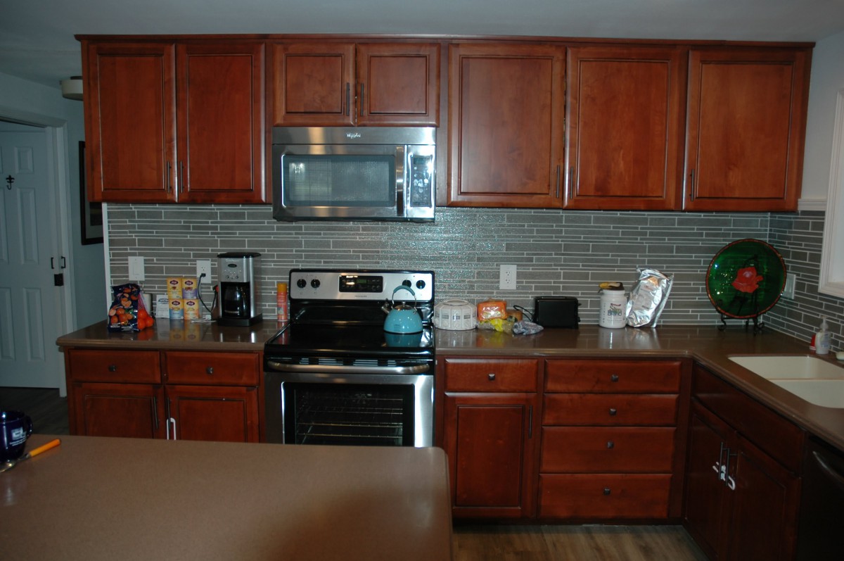 A modern kitchen with wooden cabinets, a stove, and a microwave.
