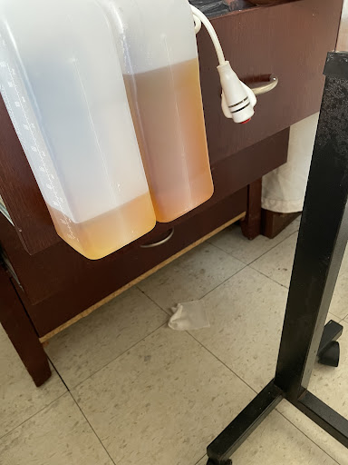 Two liquid containers are placed next to a wooden cabinet in a kitchen setting.