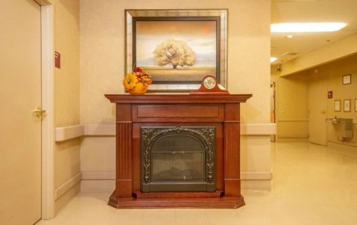 An elegant wooden fireplace adorned with a painting and decorative items on the mantel.