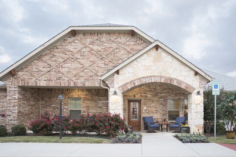 A charming brick house with a welcoming front porch and well-maintained landscaping.