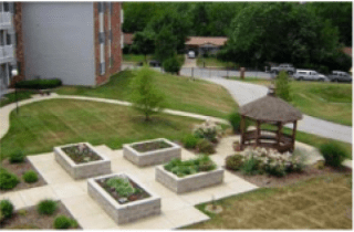 A community garden with raised beds and a gazebo in a landscaped outdoor area.