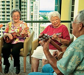A group of seniors enjoying playing ukuleles together indoors.