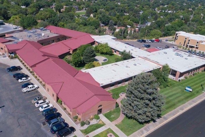 Aerial view of a school building surrounded by trees and a parking lot.