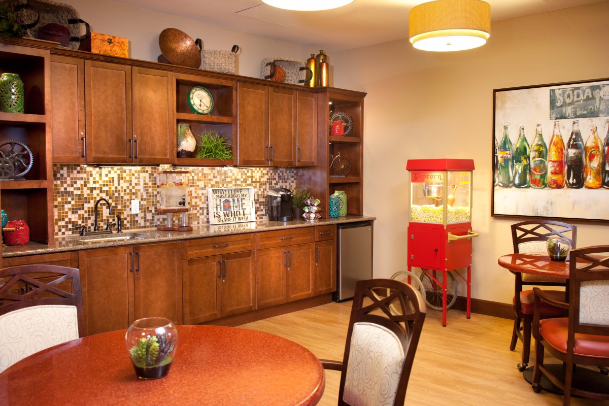 A cozy kitchen with wooden cabinets, a dining table, and a popcorn machine.