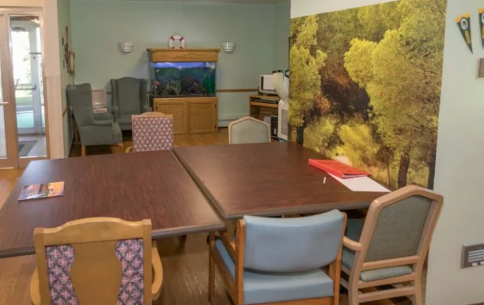 A cozy interior room with a table and chairs, featuring decorative wall art.