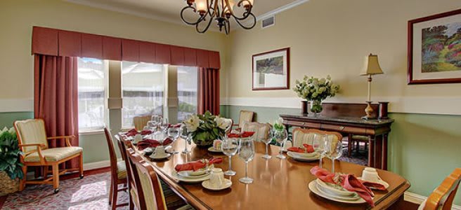 An elegantly decorated dining room with a large table set for a meal, featuring a chandelier and floral arrangements.