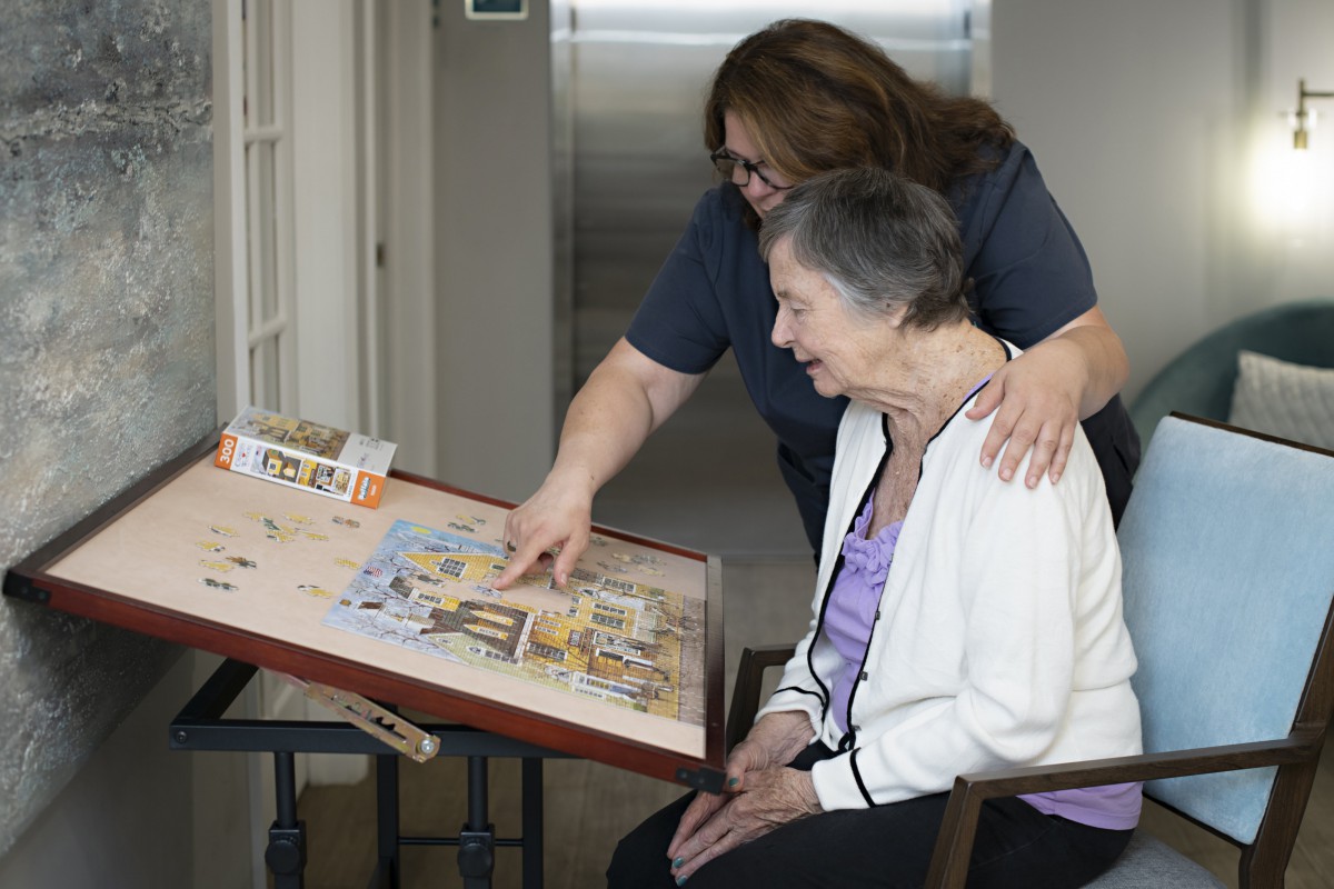 An elderly woman and a caregiver looking at a scrapbook together.