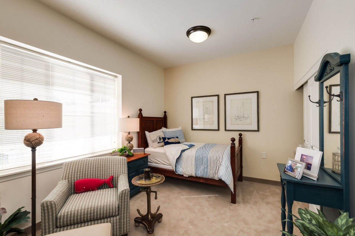 A cozy, well-lit bedroom with a bed, armchair, and elegant decor.