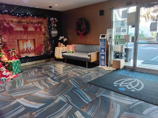 A cozy hotel lobby decorated for the holiday season, featuring a seating area and a festive fireplace backdrop.