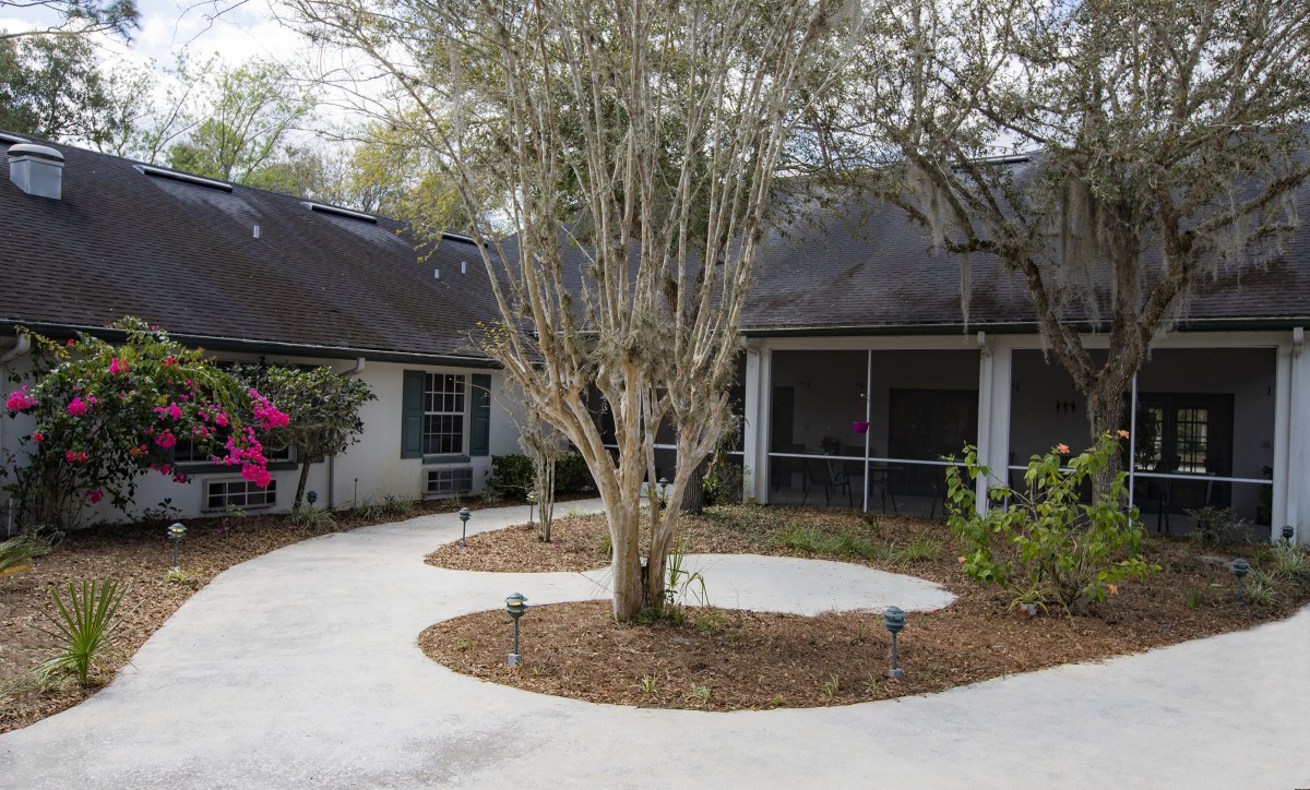 A house with a courtyard featuring a tree surrounded by landscaped pathways.