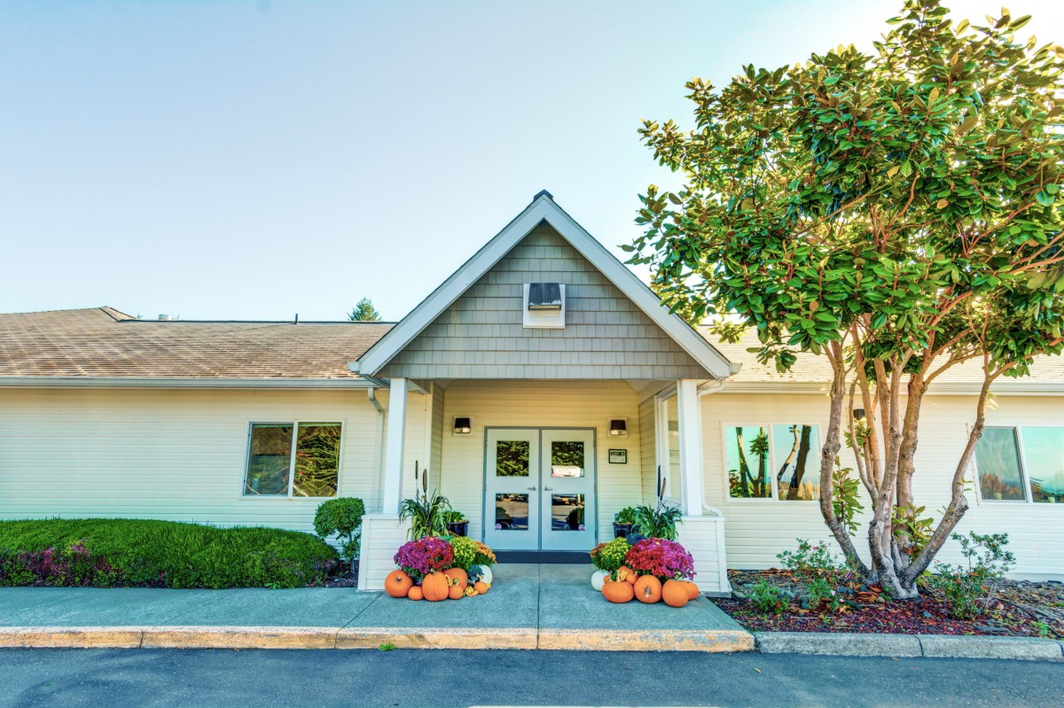 A welcoming building entrance adorned with colorful flowers and surrounded by greenery.
