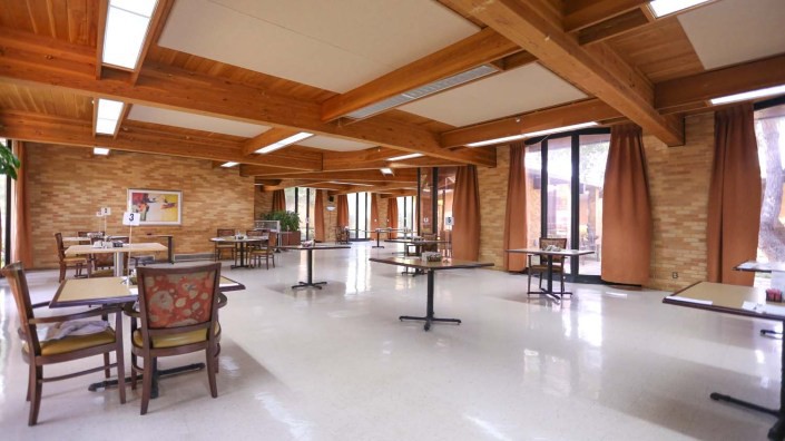 An empty dining area with wooden beams and large windows.