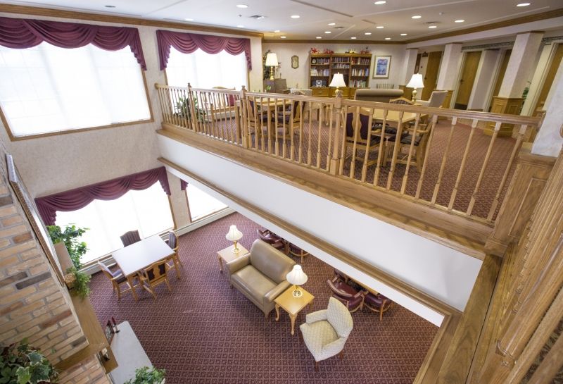 A cozy library interior with a reading area and bookshelves, featuring two levels and comfortable seating.