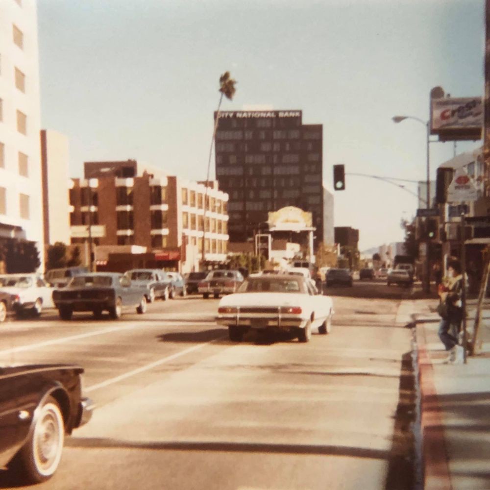 A vintage city street scene with classic cars and buildings.