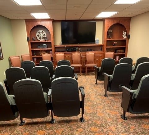 A small theater room with rows of seating facing a large screen.
