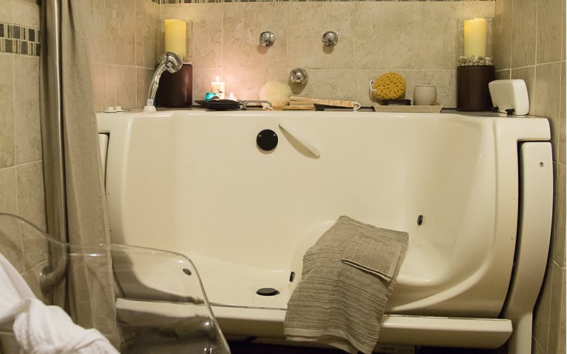 A cozy bathroom setup with a candlelit bathtub and a soft towel draped over the side.